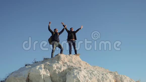 两个男子游客徒步探险登山者登山成功手把自由举起慢动作视频hike视频的预览图
