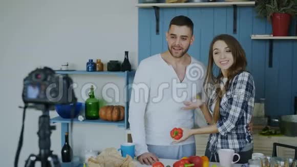 一对迷人的情侣在家里用dslr摄像机录制关于烹饪的视频食物博客视频的预览图