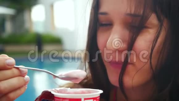 年轻漂亮的女人坐在游泳池里享受和吃酸奶3840x21604k视频的预览图