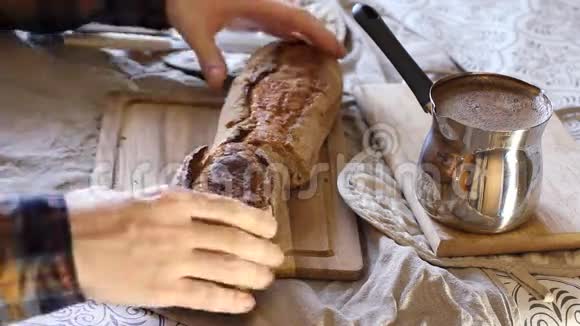 切片面包早餐桌上有黄油烤面包和牛奶咖啡一个人用刀切黑面包亚麻布视频的预览图