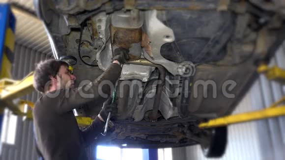 汽车修理厂桥上一辆汽车的排气口下面是一名机械师视频的预览图