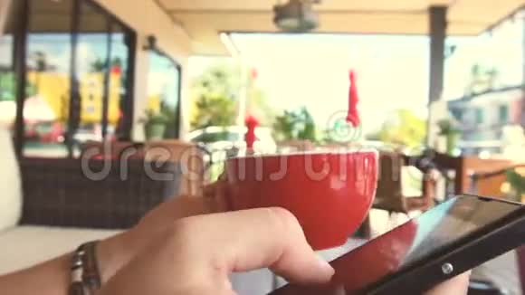 在黑手机上聊天喝红杯丁香咖啡视频的预览图