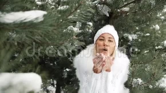 笑的女人穿着白色的裙子吹在她手上的雪上视频的预览图