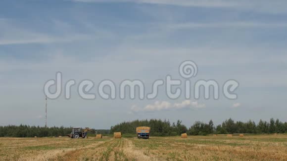农夫在拖拉机上镐草堆把一捆干草装进拖车里农业视频的预览图