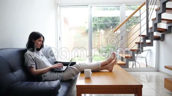 年轻女子在舒适的家里打手提电脑视频的预览图