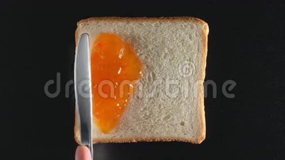 人的手把杏果酱涂在面包上视频的预览图