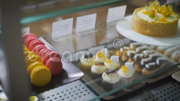 咖啡和糕点吧柜台在玻璃表面甜点是暴露的右侧多色法国马卡龙视频的预览图
