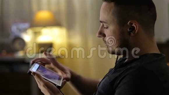 男人在家里用平板电脑看视频或听音乐视频的预览图