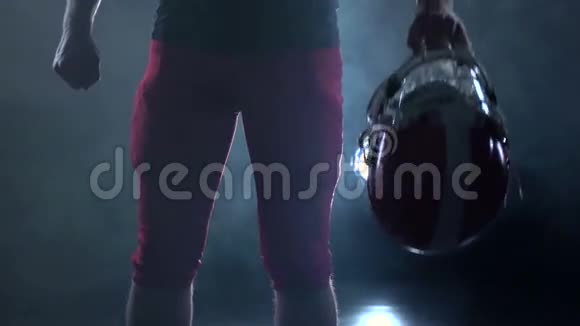 足球运动员手持红色防护头盔黑色背景慢动作视频的预览图