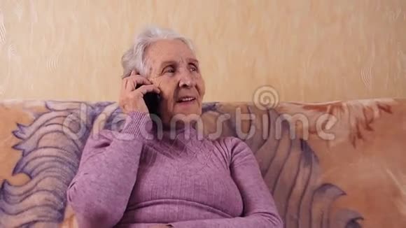 一位坐在沙发上用手机说话的老年妇女他通过手机智能手机进行交流视频的预览图