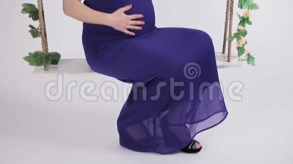 穿蓝色裙子的孕妇在秋千上视频的预览图