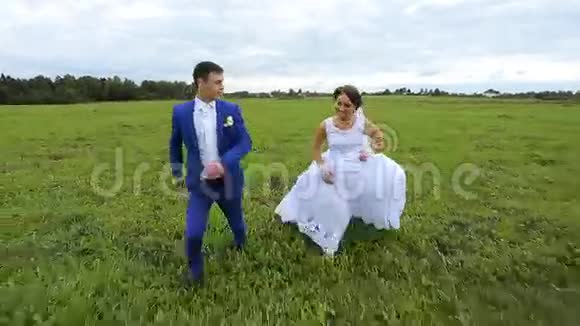 新婚夫妇在绿色的草地上奔跑视频的预览图