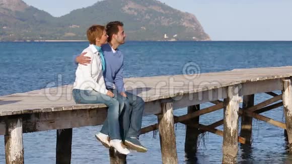 坐在码头上享受时光的美丽夫妇视频的预览图