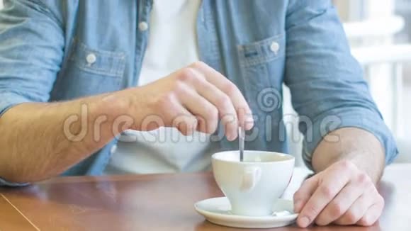 微笑的年轻人把咖啡和糖混在一起视频的预览图