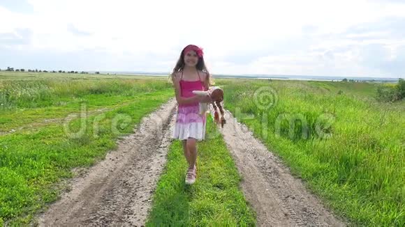 少女时代少年女孩带着一个娃娃在大自然的道路上奔跑在田野里视频的预览图