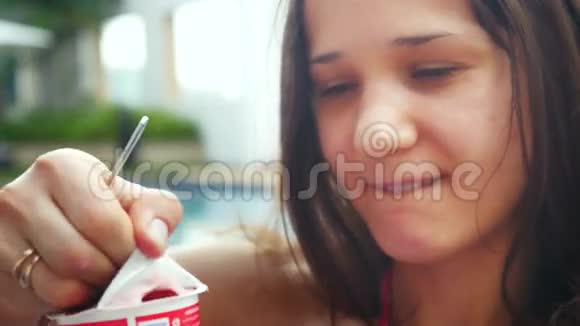 年轻漂亮的女人坐在游泳池里享受酸奶视频的预览图