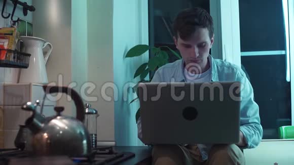 年轻人用电脑坐在厨房里烧水壶视频的预览图