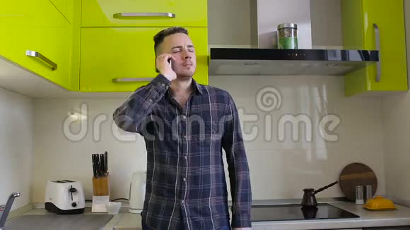一个年轻人在家里的厨房里用手机说话视频的预览图