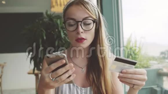 漂亮的女人用信用卡和手机购物女性在咖啡馆网上购物视频的预览图