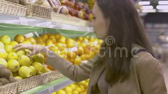 漂亮的年轻女子在超市里选择柠檬视频的预览图
