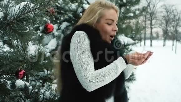 微笑的女人在寒冷的冬天用手吹雪视频的预览图
