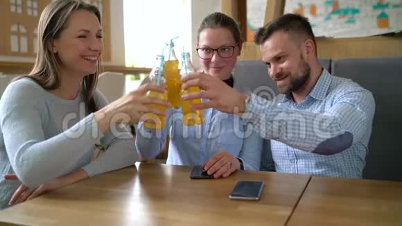 三个朋友坐在咖啡馆里喝果汁交流愉快慢动作视频的预览图