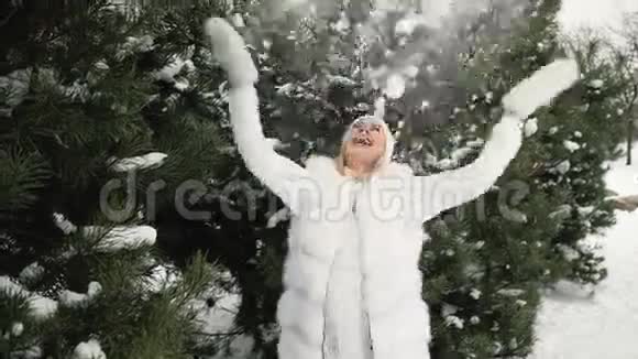 迷人的金发女郎在冬天的景色背景下玩雪视频的预览图