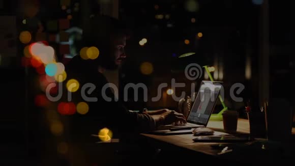 一个白人男子晚上用泡泡动画在笔记本电脑上工作视频的预览图