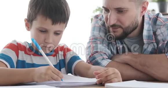 父亲帮助儿子在家学习视频的预览图