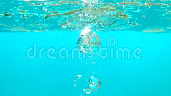 柠檬片落在蓝水中气泡在水下慢动作拍摄桌面视频的预览图