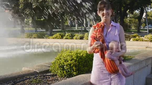 年轻妈妈带着婴儿带着智能手机微笑视频的预览图