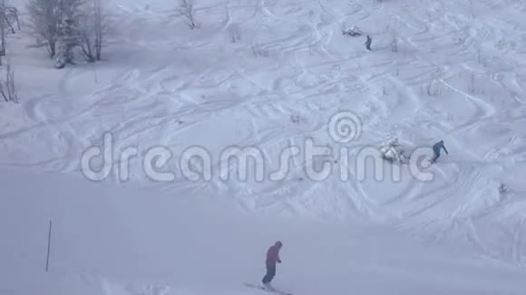 在白雪覆盖的山坡上滑雪者迅速朝不同的方向下降视频的预览图