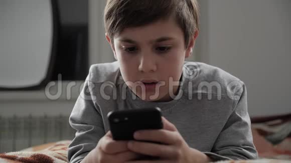 小孩在家玩手机小孩躺在床上使用智能手机视频的预览图