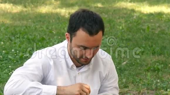 阳光明媚的一天一个人坐在美丽的绿色田野里喝水视频的预览图