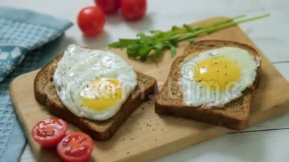 健康早餐全麦面包片上的炒鸡蛋和木条上的西红柿视频的预览图