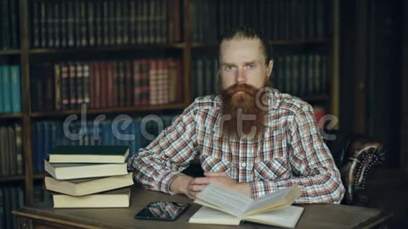 在图书馆里看镜头的一个留着胡子的年轻人视频的预览图