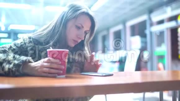 使用智能手机应用程序的女人在咖啡厅喝咖啡视频的预览图