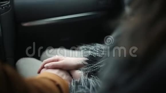 坐在车里的漂亮女孩她握住司机的手看着他和窗户侧面和背面视频的预览图