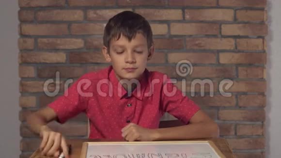 坐在办公桌前的孩子拿着一张挂图背景红砖墙上有刻字的签名视频的预览图