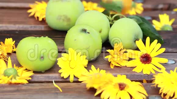 一个夏天在花园的室外老式的绿色苹果和橙色的花钉在木头表面视频的预览图
