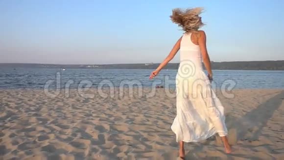 穿着白色裙子在沙滩上跳舞的女人视频的预览图