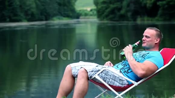 躺在湖边的躺椅上喝酒的年轻人正在谈论视频的预览图