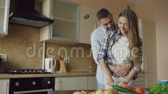 快乐的年轻夫妇在厨房里拥抱和交谈在家做早餐视频的预览图