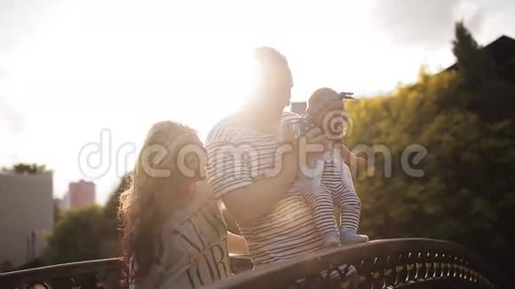 日落时分公园的桥上有个孩子的年轻父母视频的预览图
