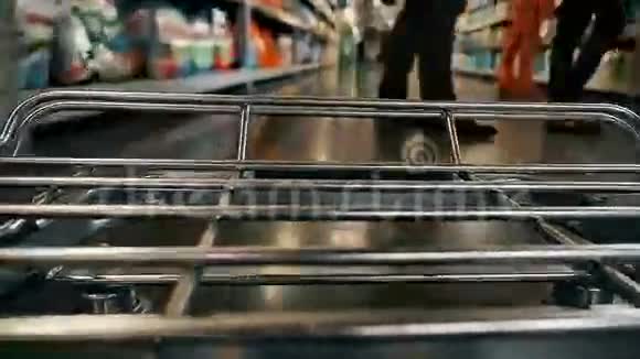 大型超市购物车的加速延时视频在模糊的货架之间移动颜色分级视频的预览图