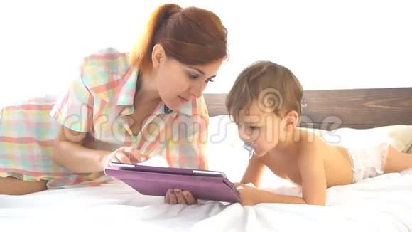 母亲和年幼的儿子在卧室里享受着互联网上的平板电脑视频的预览图