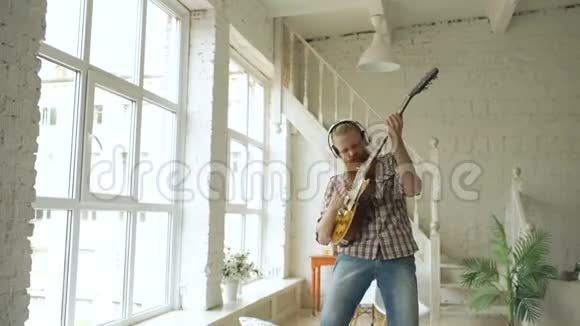 有趣的大胡子男人在床上跳舞在卧室里唱歌弹电吉他视频的预览图