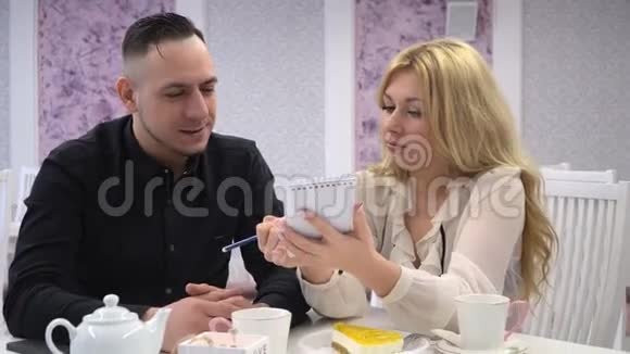 在咖啡馆里相爱的一对两个男人和女人在可爱的咖啡馆里聊天写在笔记本上视频的预览图