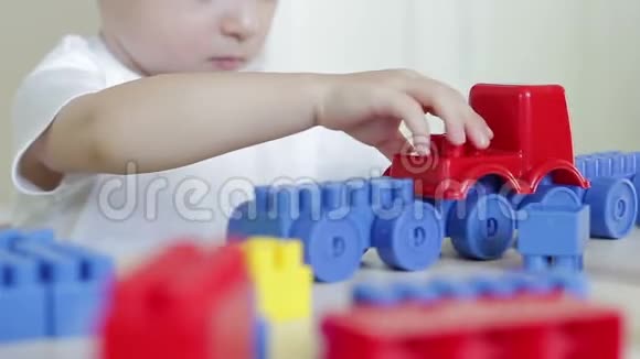 桌子旁的孩子玩玩具车和彩色积木视频的预览图