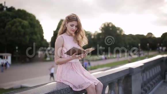 女孩坐在公园的岩石上看书用手纠正长发视频的预览图